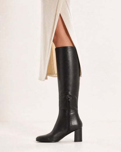 Women's black knee-high boots with a broad block heel, lateral profile.