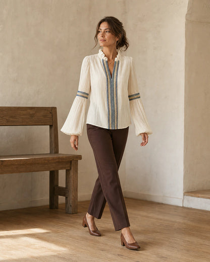 Women's ivory vintage blouse in a warm architectural lifestyle setting.