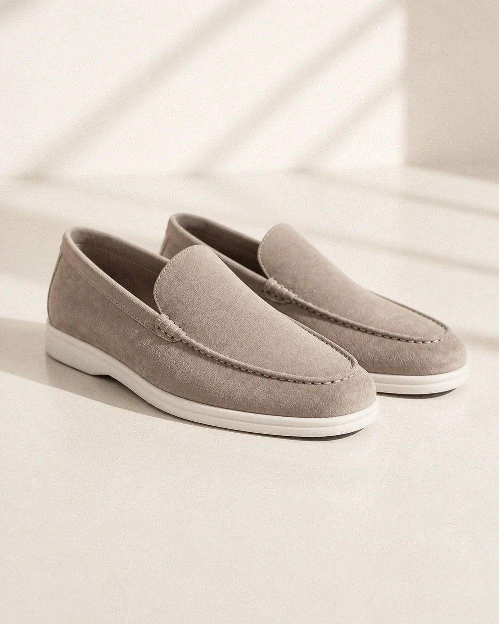 Pair of beige suede-effect slip-on loafers on a neutral studio background.